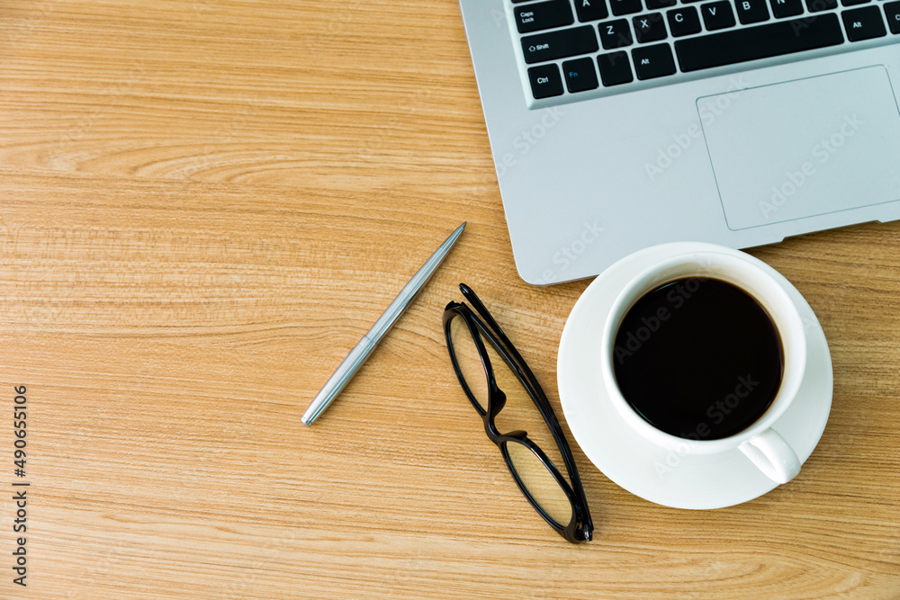 Desk with laptop, coffee, pen and eyeglasses Desk with laptop, coffee, pen and eyeglasses