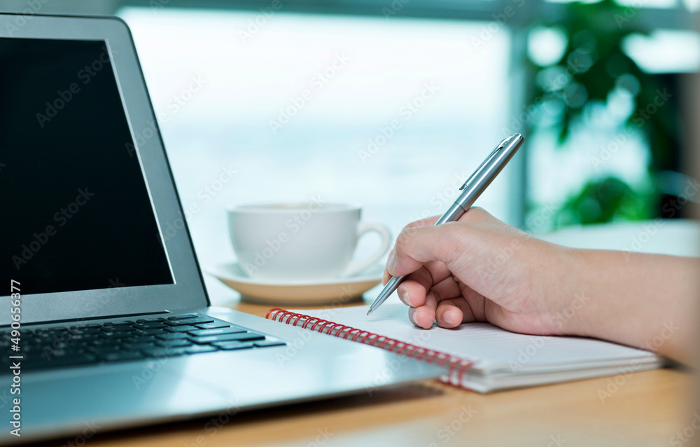 People using laptop and writing notebook at workplace People using laptop and writing notebook at workplace