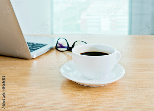 Office desk with laptop, coffee and glasses on wooden table