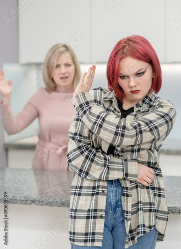 Family conflict. Angry mother screams at afraid teen daughter, girl ignoring her mom and shows stop gesture. Family relationships