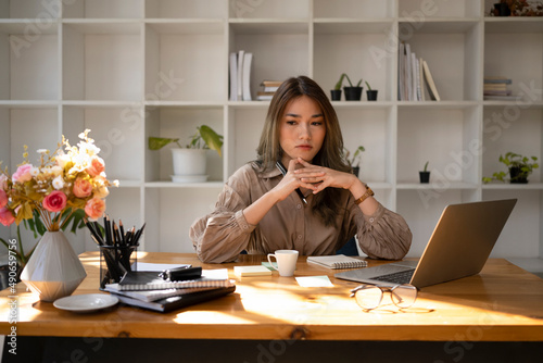 Thoughtful businesswoman sitting at her workplace and pondering project problem solution.