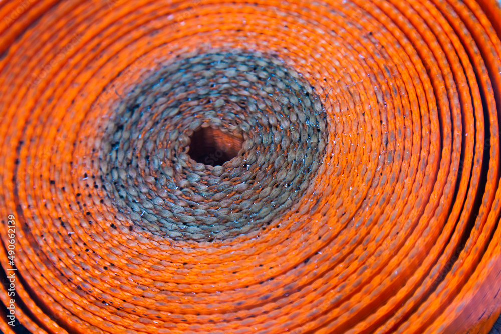 Fototapeta premium Twisted orange belt for securing cargo, close-up.
