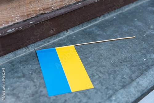 Small hand Ukrainian flag placed on the windowsill.