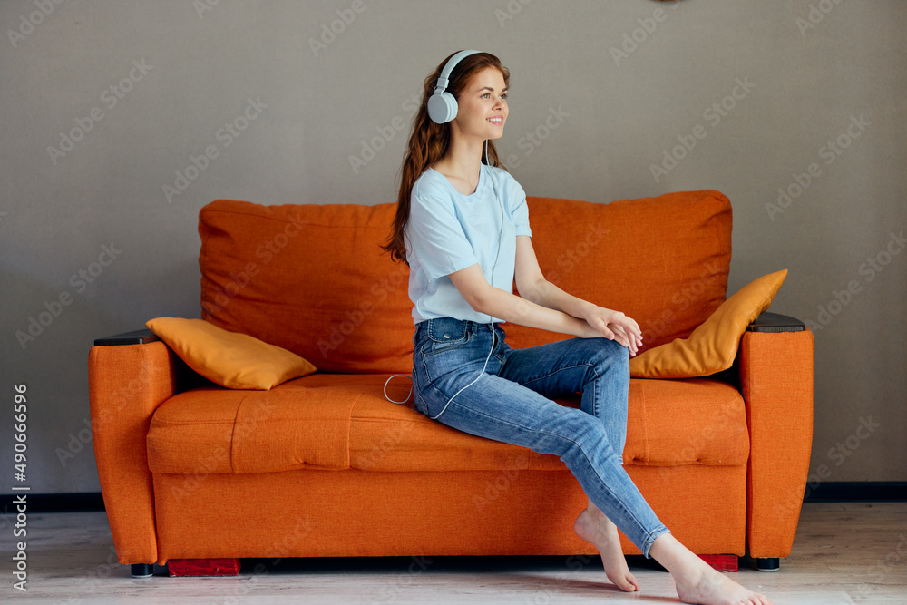 Obraz premium beautiful woman sitting on the couch at home listening to music on headphones Lifestyle