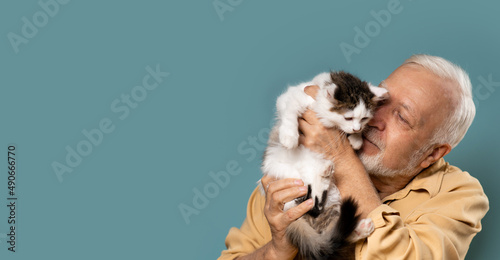 an elderly man holds a small kitten in his hands, love, care, light blue background, banner, space for text