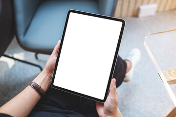 Mockup image of a woman holding digital tablet with blank white desktop screen in cafe