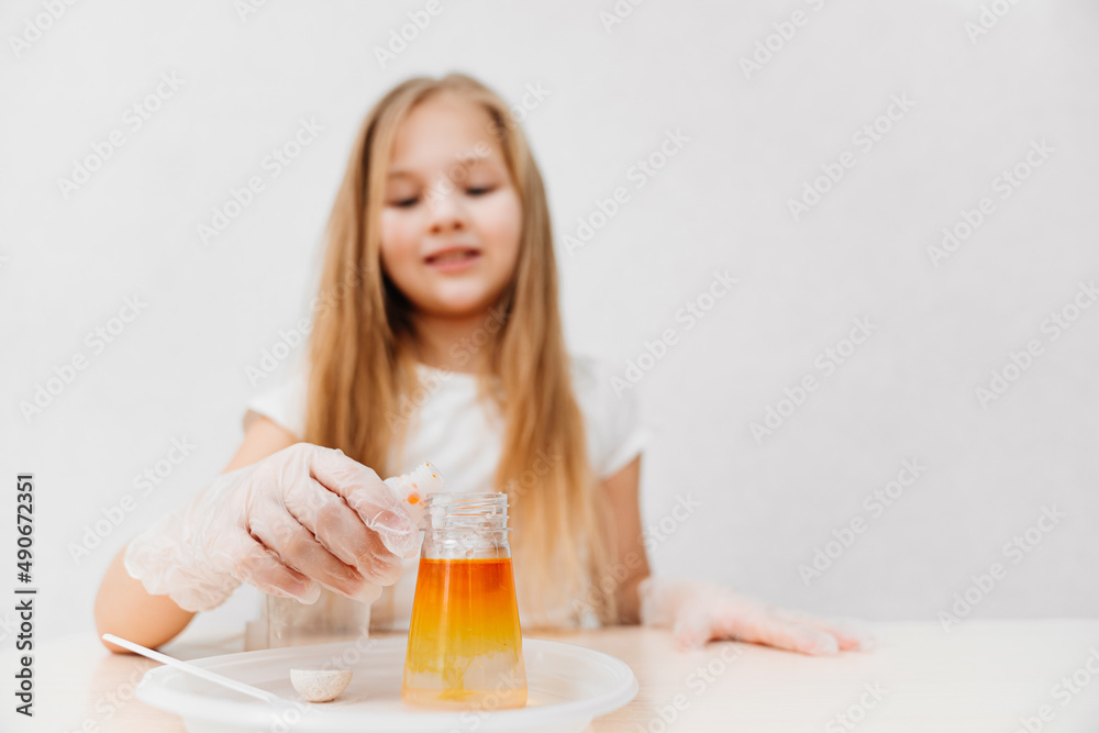 a cute little girl conduct an experiments at home. flask with colored liquid a cute little girl conduct an experiments at home. flask with colored liquid