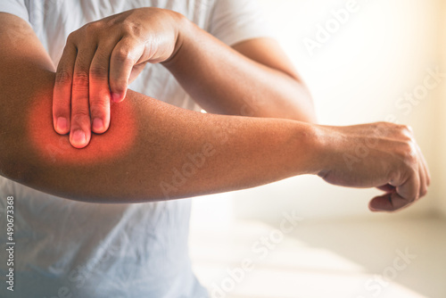 Tennis elbow concept. The man uses fingers to massage his arm. Healthcare knowledge. Medium close up shot.
