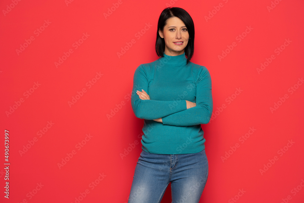Portrait of happy beautiful middle aged woman with black hair in blue blouse and jeans . indoor studio shot isolated on red Portrait of happy beautiful middle aged woman with black hair in blue blouse and jeans . indoor studio shot isolated on red