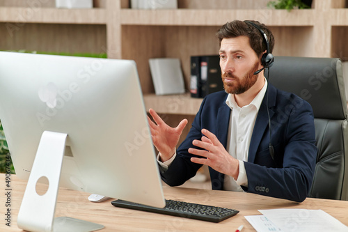 Obraz na plátně Representive practitioner leads online training wearing a suit and headset, with