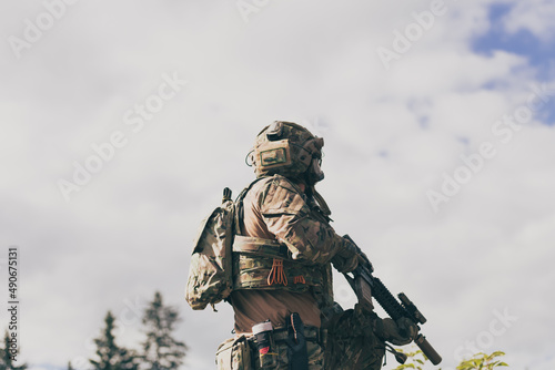 War concept. A bearded soldier in a special forces uniform fighting an enemy in a forest area. Selective focus 