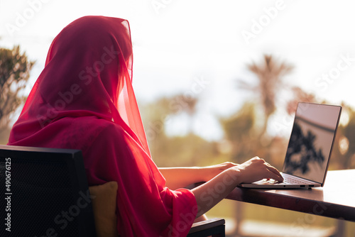 Fototapet Silhouette of muslim, arab woman freelancer in red head scarf, hijab sitting at