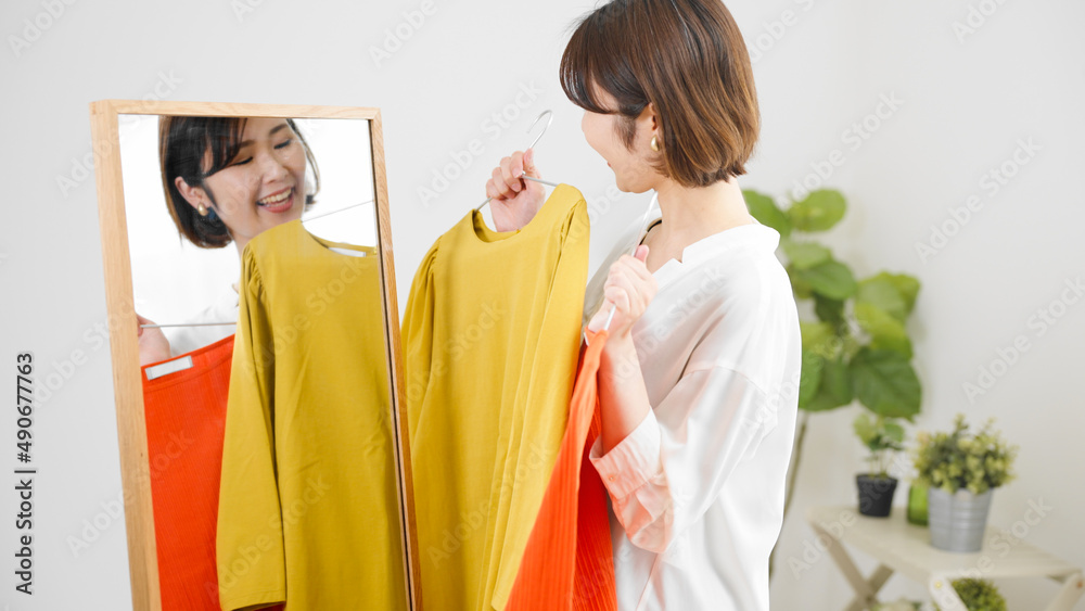 鏡の前で服選びをしている若い女性　ファッションイメージ