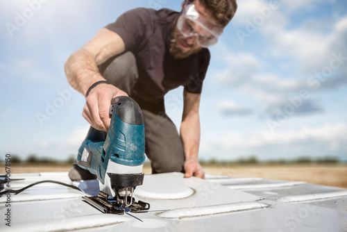 Man working with a jigsaw on the roof of a van