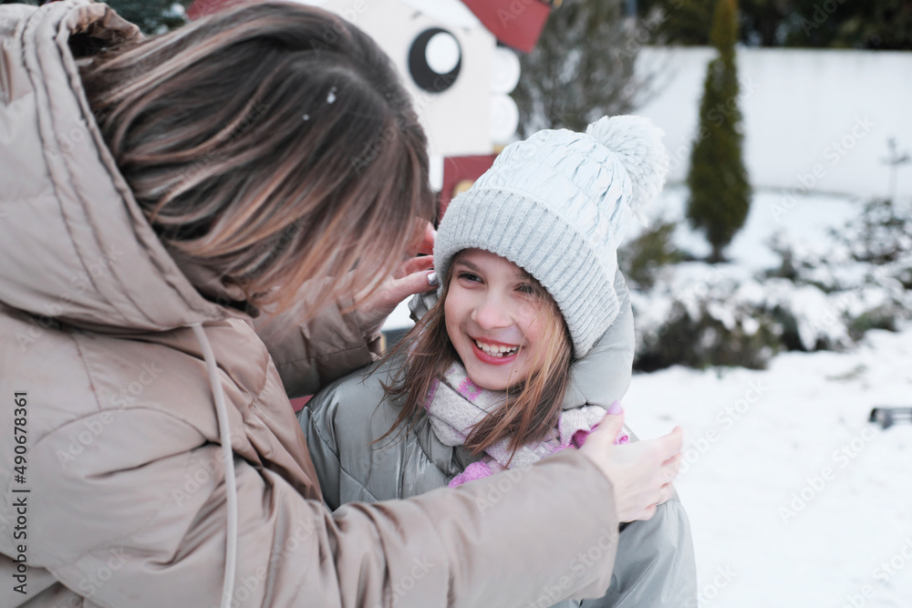 portrait of caring mother adjusting hat on cue girl while enjoying walk together outdoors in winter portrait of caring mother adjusting hat on cue girl while enjoying walk together outdoors in winter