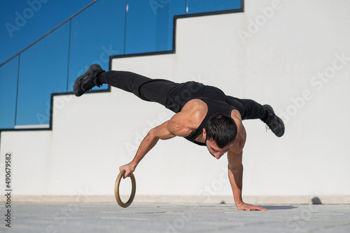 Wallpaper Mural A man in black sportswear does an acrobatic handstand on a ring outdoors
