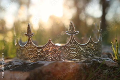 mysterious and magical photo of silver king crown in the woods over stone. Medieval period concept.
