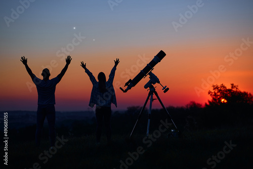 Couple stargazing together with a astronomical telescope.