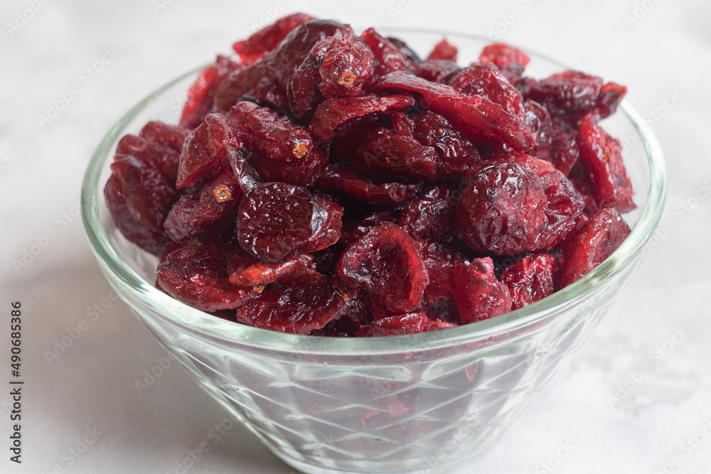 dried cranberries in a glass bowl on a concrete background. Close-up. Selective focus. dried cranberries in a glass bowl on a concrete background. Close-up. Selective focus.