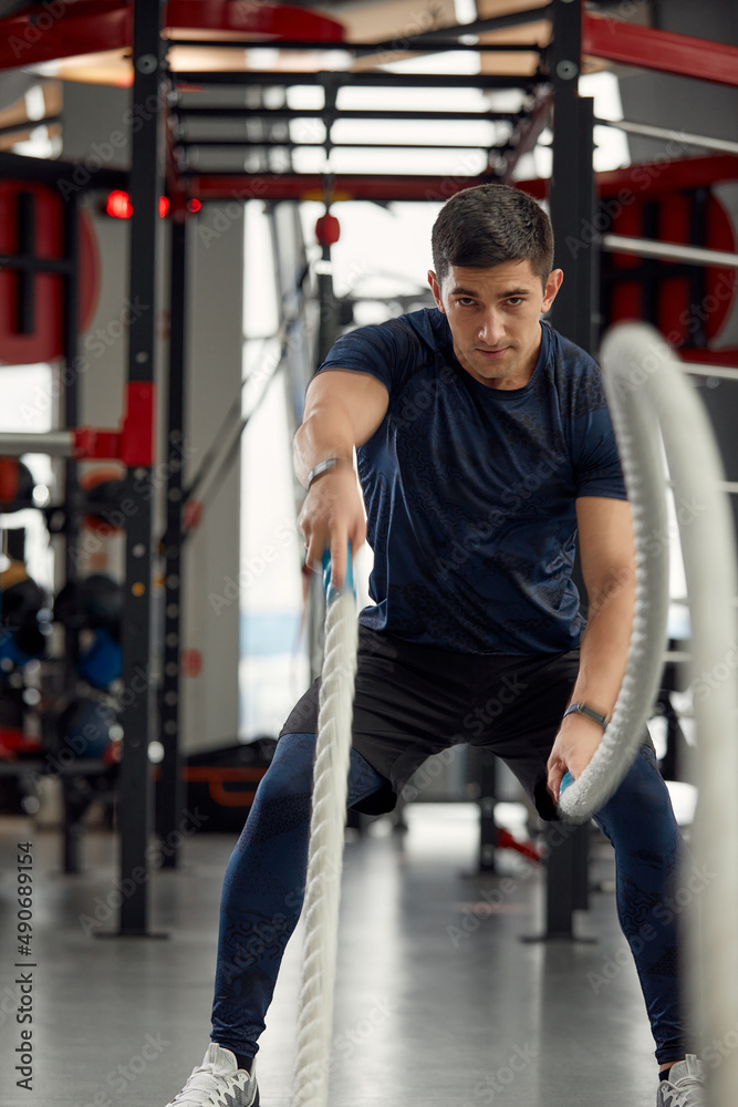Man holding a pair of battle ropes for workout. guy at the gym working out with fitness rope. Man holding a pair of battle ropes for workout. guy at the gym working out with fitness rope.