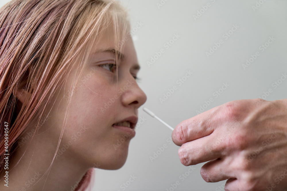 Teenage girl while doing rapid antigen test nasal swab. Rapid diagnostic test kit Teenage girl while doing rapid antigen test nasal swab. Rapid diagnostic test kit