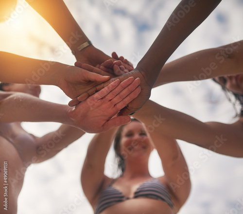 Living the adventure together. Low angle shot of a group of young friends putting their hands in a pile outside.