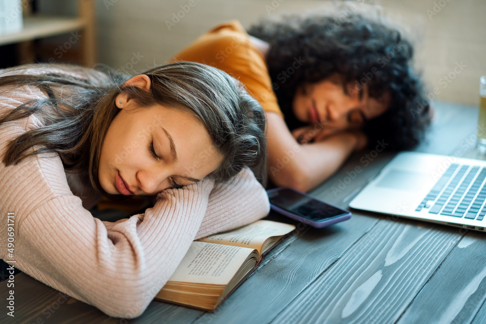 Tired diverse teenage girls and friends fell asleep as they prepared for the exam. Tired diverse teenage girls and friends fell asleep as they prepared for the exam.