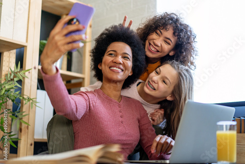 Happy african american mother and teen daughters using smartphone apps for shopping social media © NDABCREATIVITY