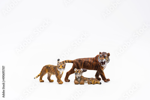 Toy animal figures tiger and tiger cubs on white.	