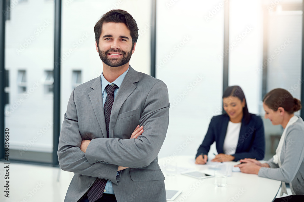 Hes leading the way forward. Portrait of a businessman standing in a boardroom meeting with colleagues in the background. Hes leading the way forward. Portrait of a businessman standing in a boardroom meeting with colleagues in the background.
