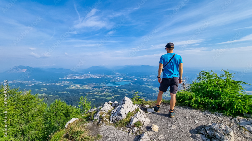 Man admiring the scenic view from summit of Ferlacher Spitze on Mittagskogel in the Karawanks, Carinthia, Austria. Borders between Austria, Slovenia, Italy. Rosental valley. Hiking adventure, freedom
