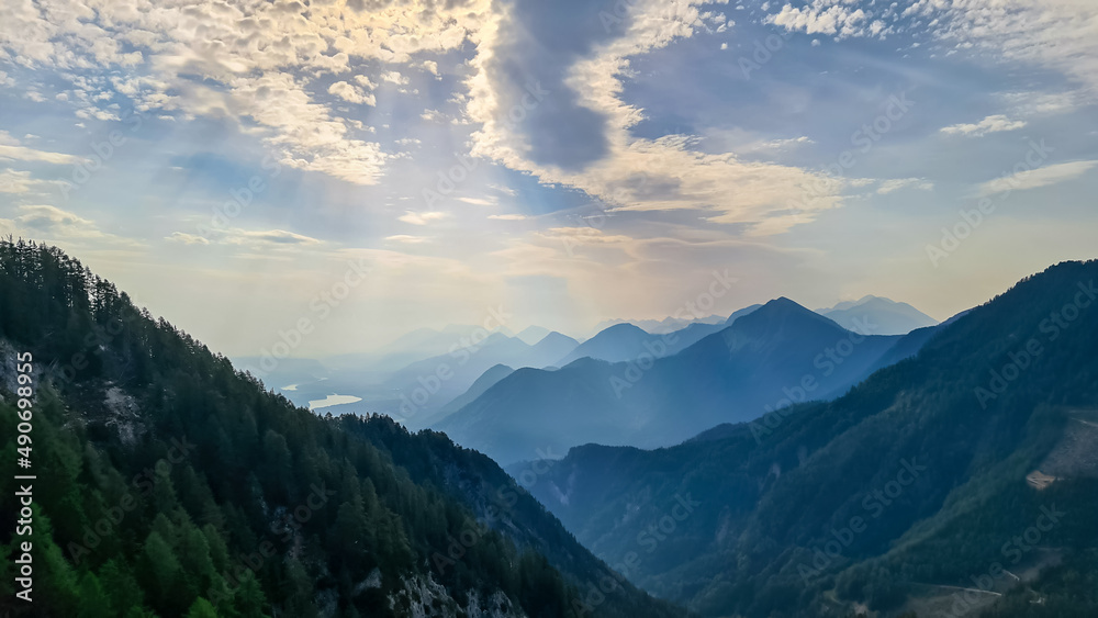 Scenic view on the alpine mountain chains and woodland of the Karawanks in Carinthia, Austria. Peaks are shrouded in morning fog. Mystical vibes. Ssunny day. Serenity. View from Ferlacher Spitze, Alps