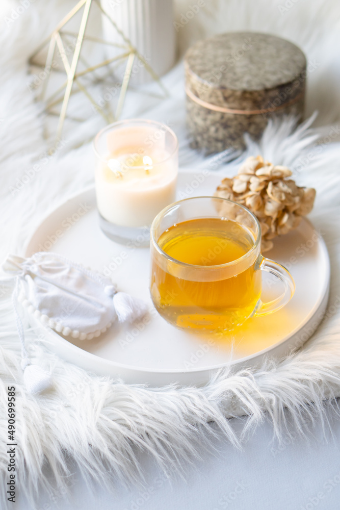 Cup of herbal tea and burning candle on round white decorative tray Cup of herbal tea and burning candle on round white decorative tray