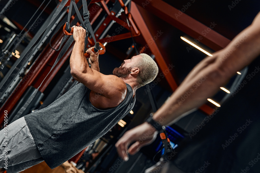 A man trains his arms and chest in the gym on the simulator, does exercises for different muscle groups. Fintes motivation, sports lifestyle, health, athletic body, body positive. Film grain. A man trains his arms and chest in the gym on the simulator, does exercises for different muscle groups. Fintes motivation, sports lifestyle, health, athletic body, body positive. Film grain.