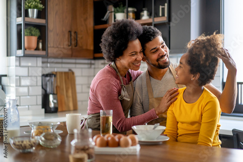 Overjoyed young african american family with daughter having fun in kitchen together