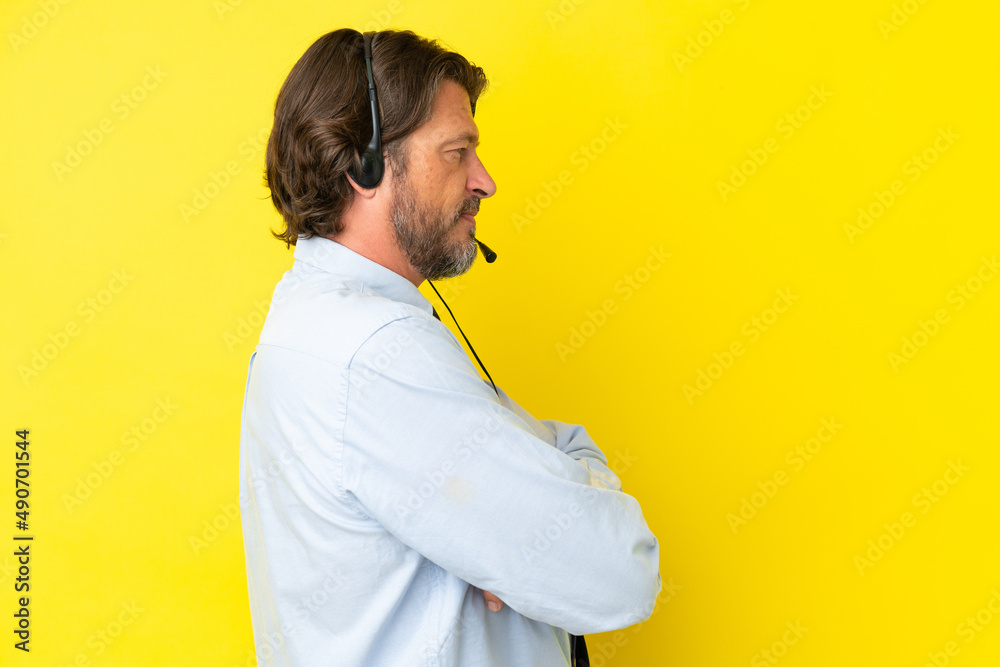 Telemarketer dutch man working with a headset isolated on yellow background in lateral position Telemarketer dutch man working with a headset isolated on yellow background in lateral position