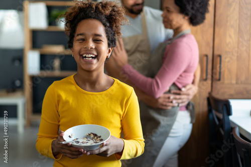 Overjoyed young multiethnic family with daughter having fun in kitchen together