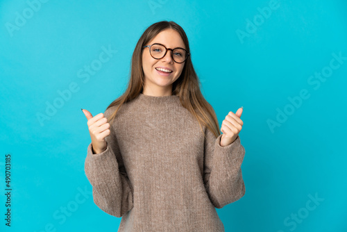 Young Lithuanian woman isolated on blue background with thumbs up gesture and smiling