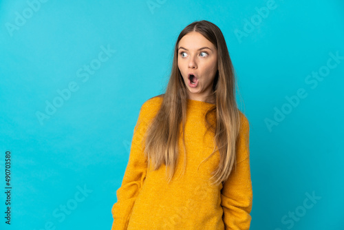 Young Lithuanian woman isolated on blue background doing surprise gesture while looking to the side