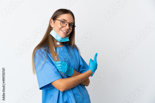 Lithuanian woman dentist holding tools over isolated background pointing back