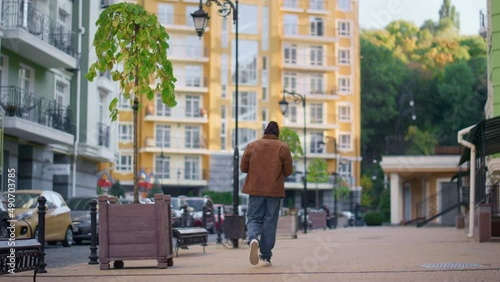 Wallpaper Mural Casual man walking city modern residential area rear view. Lonely walker concept Torontodigital.ca