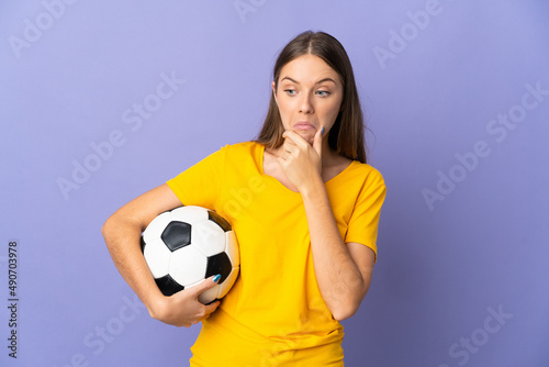 Young Lithuanian football player woman isolated on purple background having doubts © luismolinero