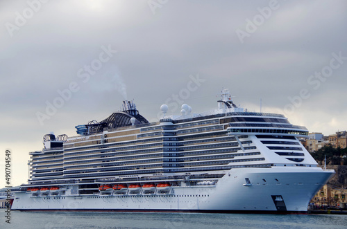 Mega modern MSC cruiseship or cruise ship liner in port of Valletta, Malta island with panoramic scenic view of historic old town, city walls and fortress skyline on summer day during Med cruising photo