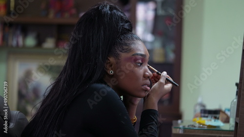 One African girl applying make up in front of mirror