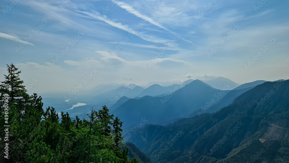 Fototapeta premium Scenic view on the alpine mountain chains of the Karawanks in Carinthia, Austria. Peaks are shrouded in morning fog. Mystical vibes. Clear and sunny day. Serenity. View from Ferlacher Spitze, Alps
