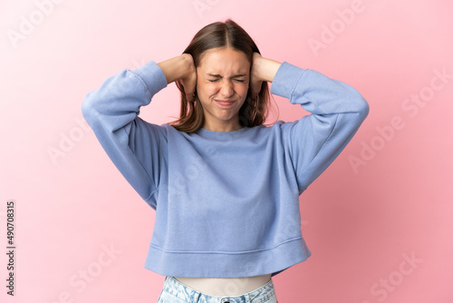Young woman over isolated pink background frustrated and covering ears © luismolinero