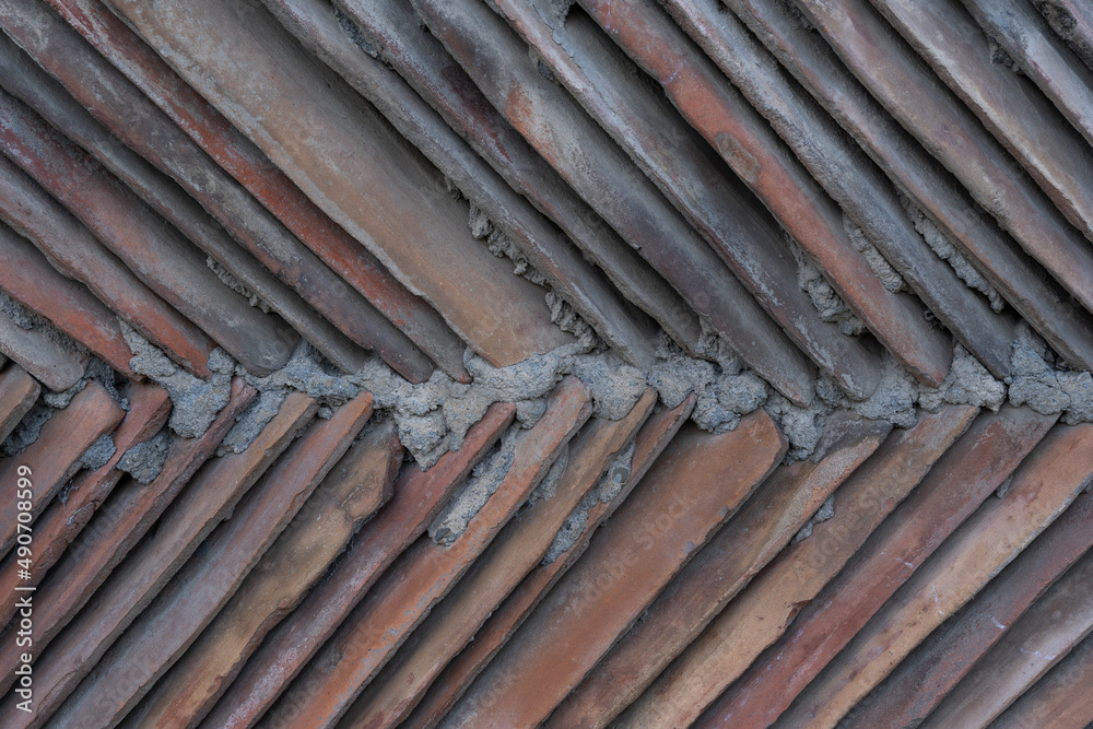 brown clay tiles walled together with concrete form a triangular shape and structure. brown clay tiles walled together with concrete form a triangular shape and structure.