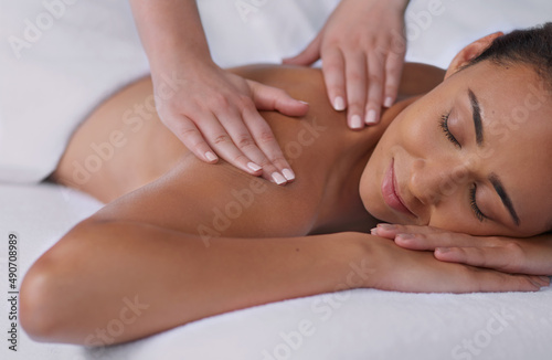 The perfect stress reliever. Shot of a beautiful young woman enjoying a back massage at a spa.