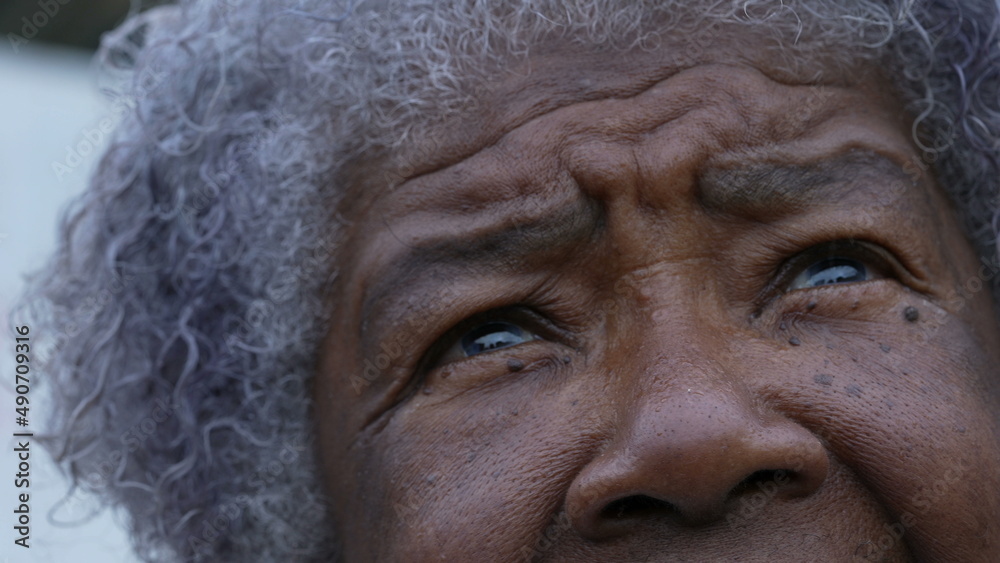 An African older woman looking up at sky with HOPE and FAITH macro eyes face closeup