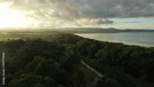 Aerial shot of a beautiful long beach in costa rica. Sunny day close to the pacific ocean and the tropical forest photo